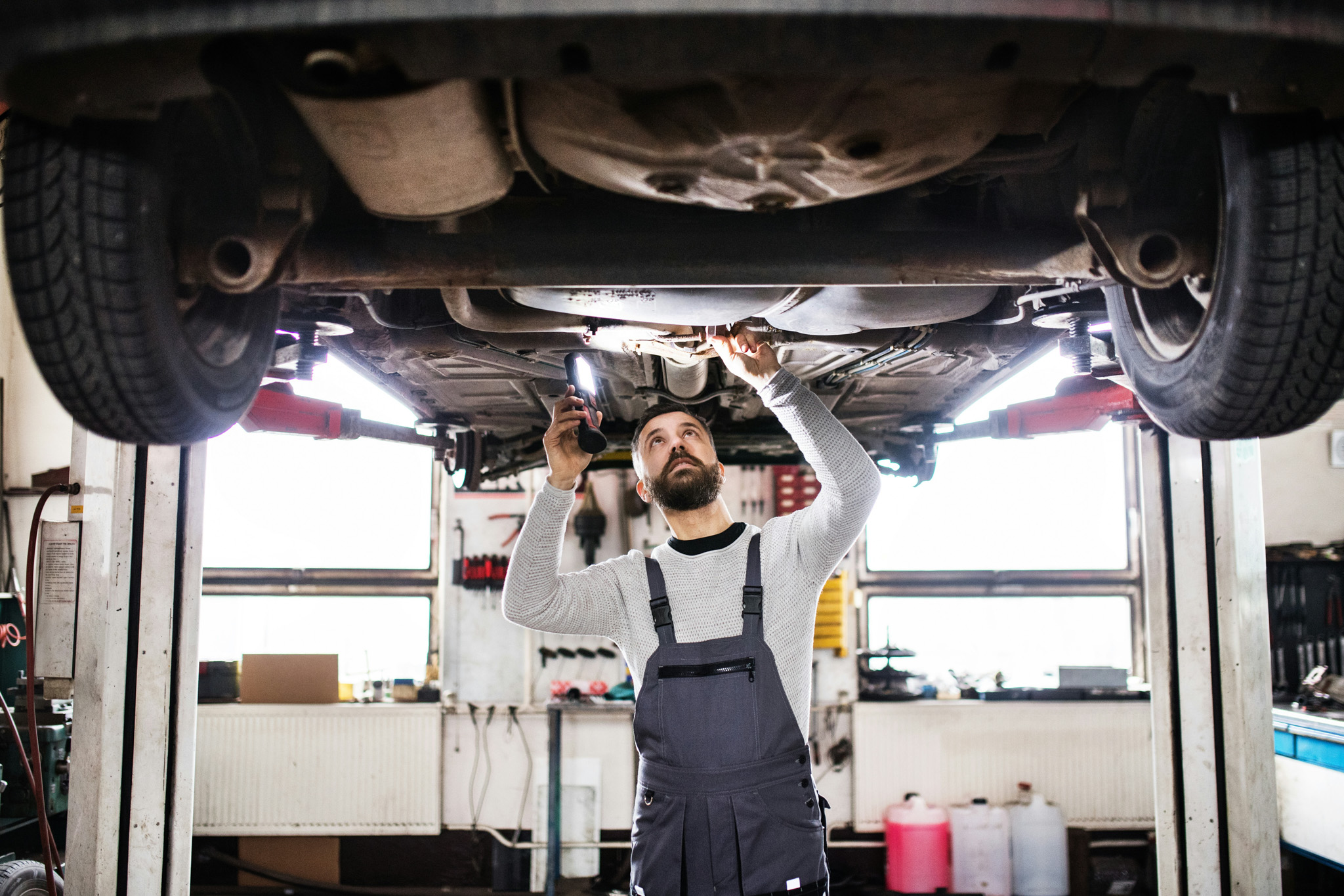 This image shows a mechanic underneath a suspended vehicle tuning the suspension.